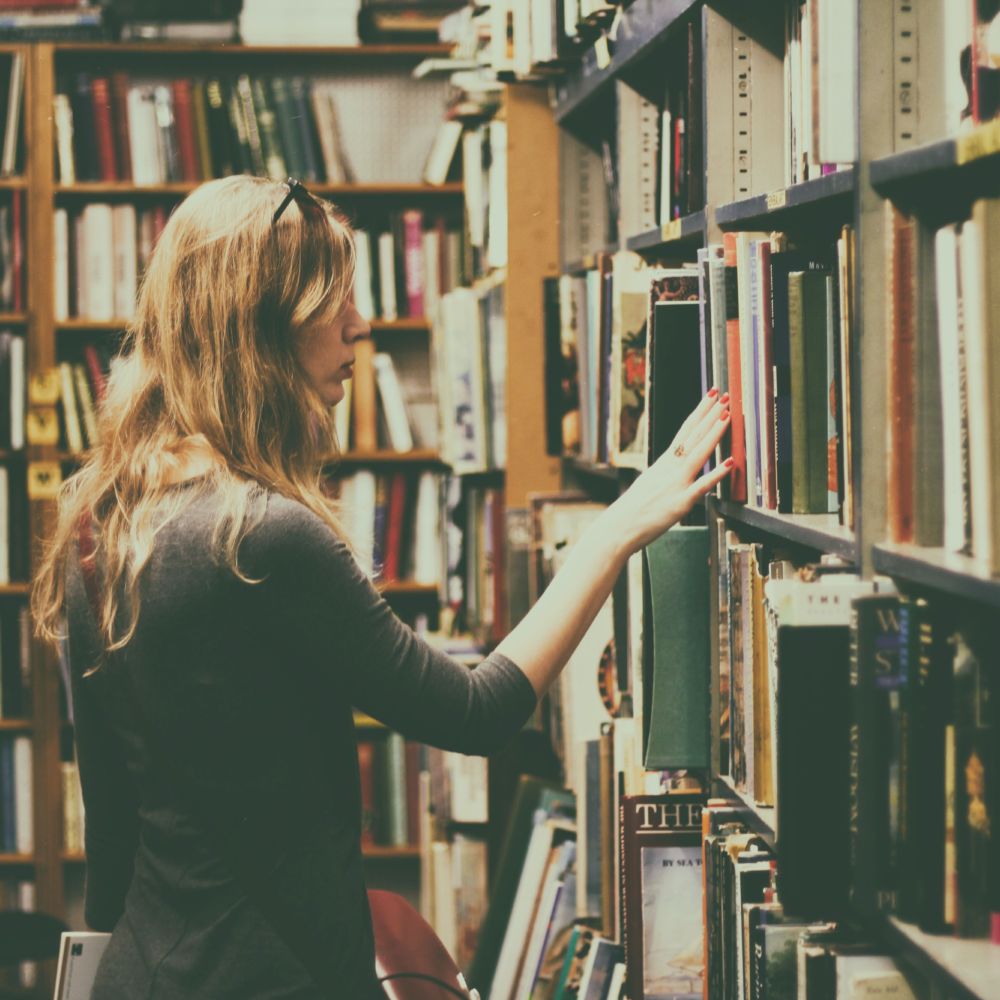 woman-in-black-long-sleeved-looking-for-books-in-library-926680
