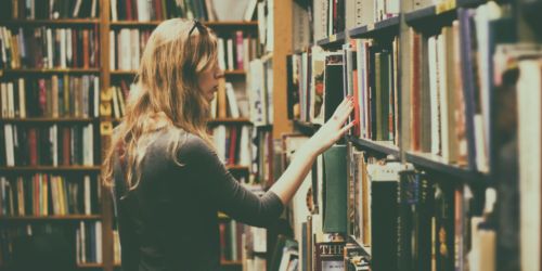 woman-in-black-long-sleeved-looking-for-books-in-library-926680